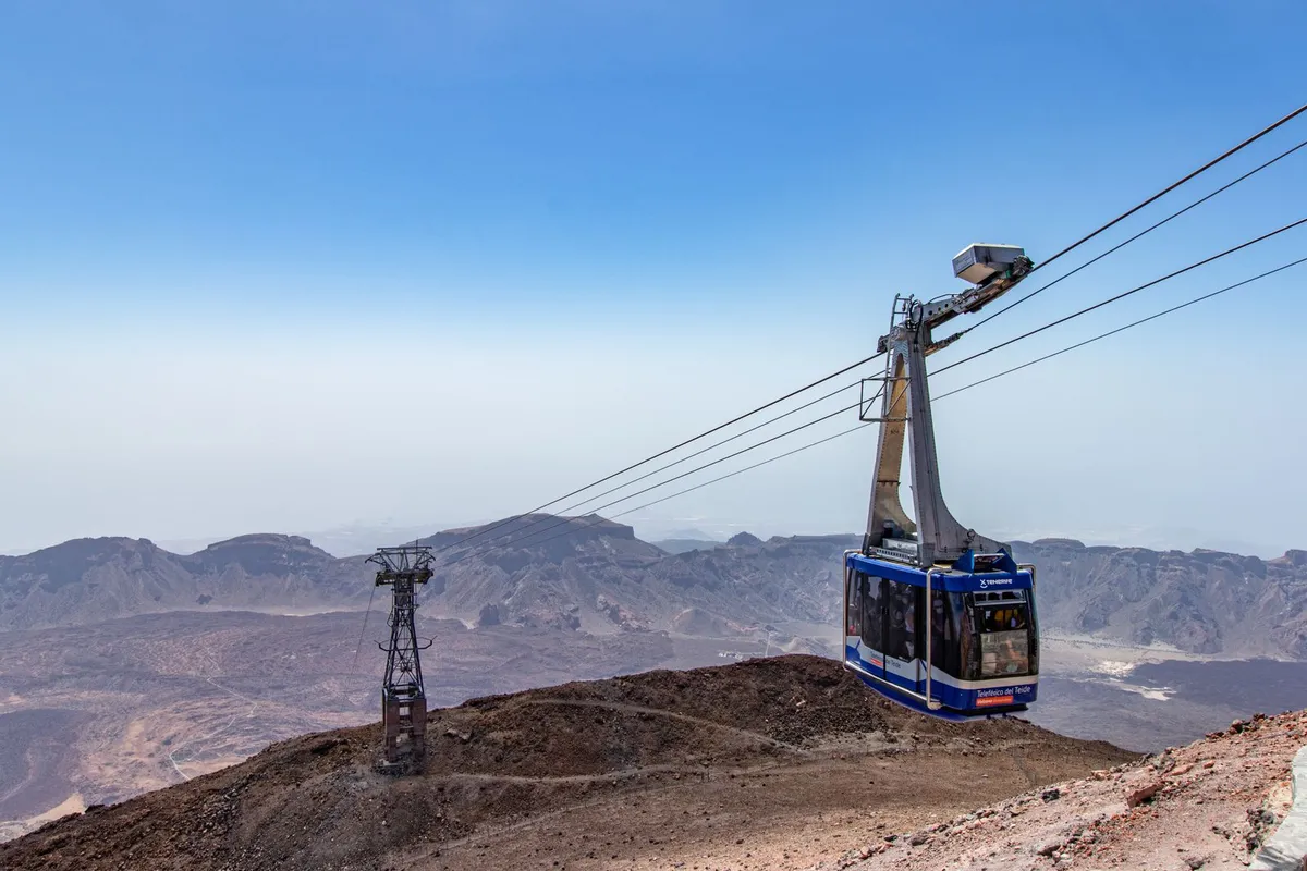 A Teide cable car cabin climbing the pylon line above the volcanic ridges of the national park