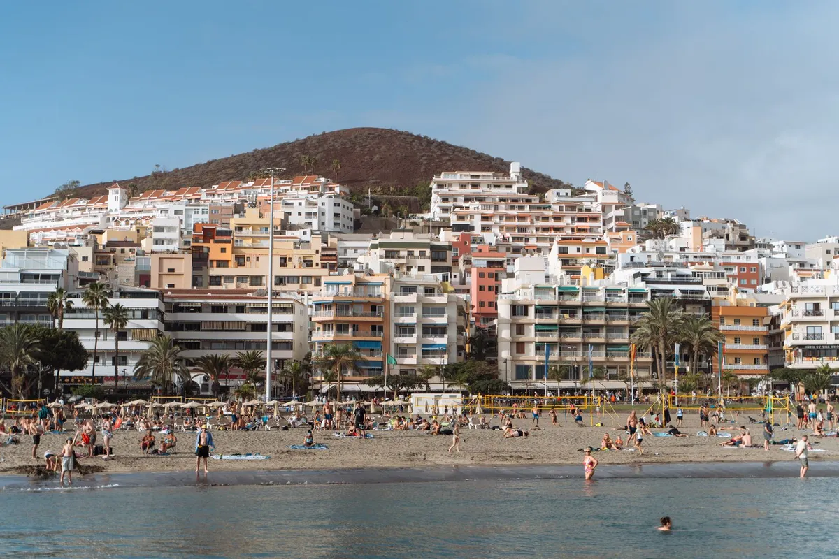 Sunbathers on the sand and swimmers in the sea along the Tenerife south coast