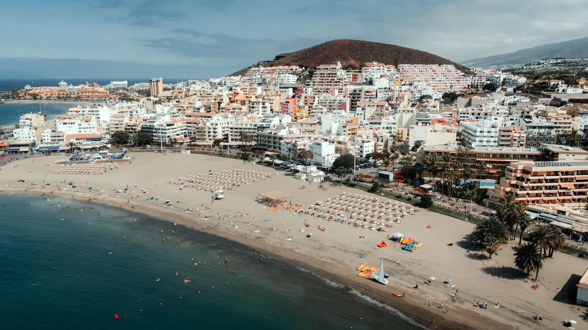 Aerial view of the sunny south-coast resort belt and beach at Los Cristianos, Tenerife
